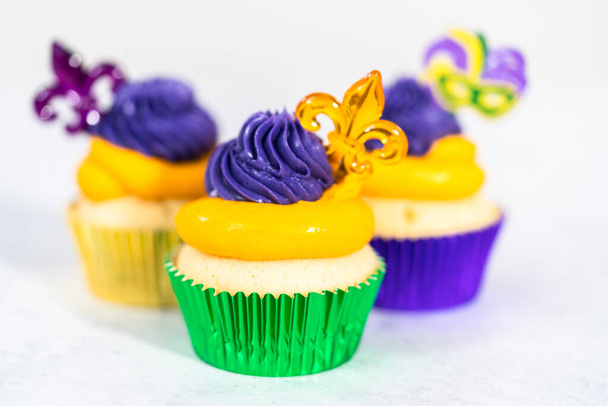 Mardi Gras vanilja cupcakes folio cupcake kupit ja koristeltu Italian buttercream kuorrutus. - Valokuva, kuva