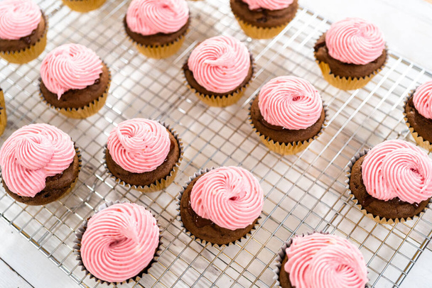 Frosting chocolate cupcakes with raspberry cream cheese buttercream. - Photo, Image