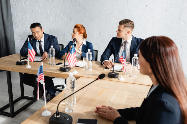 Monikansalliset poliitikot puhuvat puoluekokouksessa istuessaan pöydällä USAn lippujen kanssa - Valokuva, kuva