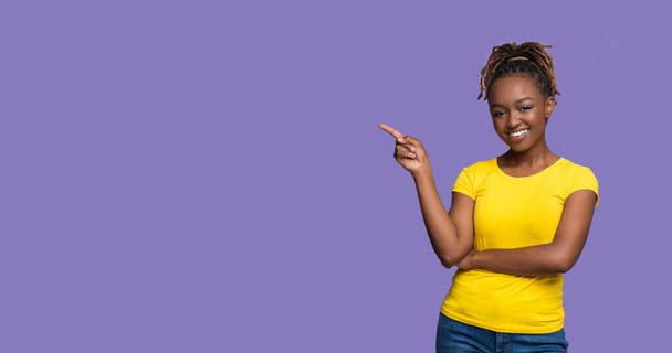 Heureuse femme noire pointant vers l'espace de copie sur violet - Photo, image