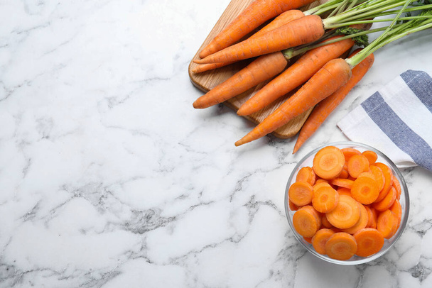 Whole and cut ripe carrots on white marble table, flat lay. Space for text - Photo, image