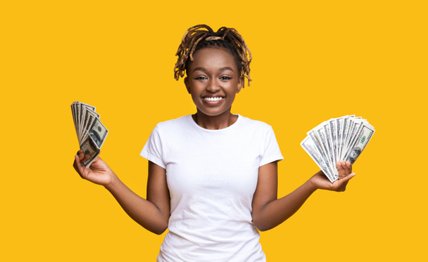 Érzelmi afro-amerikai nő, aki mindkét kezében tartja a pénzt. - Fotó, kép