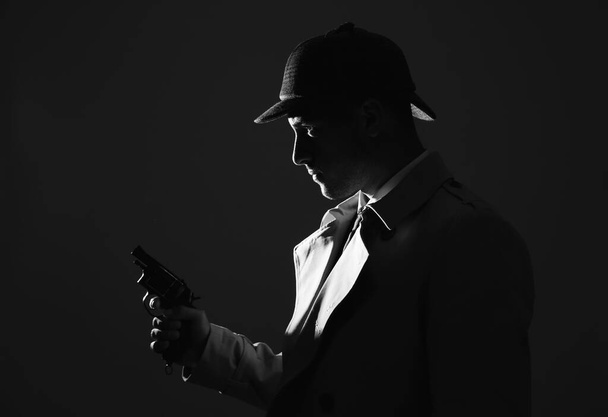 Old fashioned detective with revolver on dark background, black and white effect - Фото, изображение