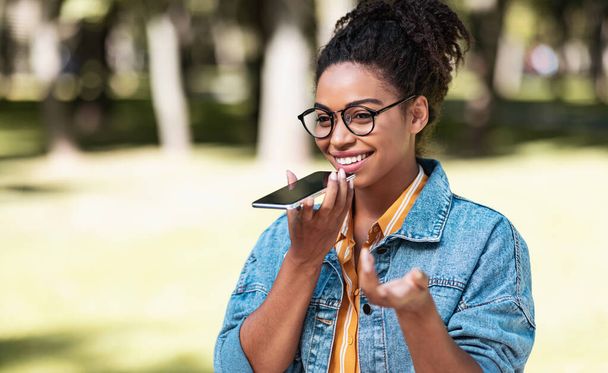 Glückliche schwarze Dame spricht per Handy über Lautsprecher im Freien - Foto, Bild