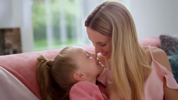 Cute girl and happy mother touching noses. Smiling woman playing with daughter - Footage, Video