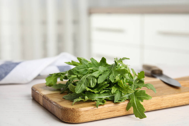 Fresh arugula, cutting board and knife on table indoors. Space for text - Fotó, kép
