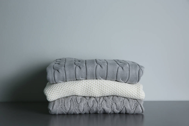 Stack of folded knitted sweaters on grey table - Фото, зображення