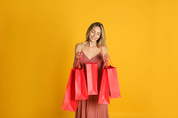Happy young woman with shopping bags on yellow background. Black Friday Sale - Foto, Bild