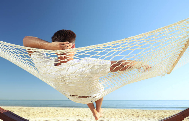 Man relaxing in hammock on beach. Summer vacation - Fotó, kép