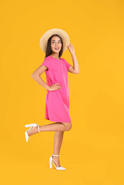Young woman wearing stylish pink dress on yellow background - 写真・画像