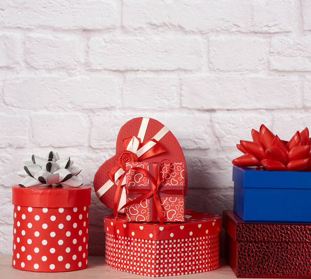 stapel van verschillende dozen met geschenken op witte baksteen achtergrond, feestelijke achtergrond - Foto, afbeelding
