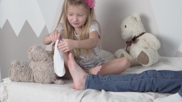 De jongere zus trekt vrolijk de oudere broer sokken aan - Video