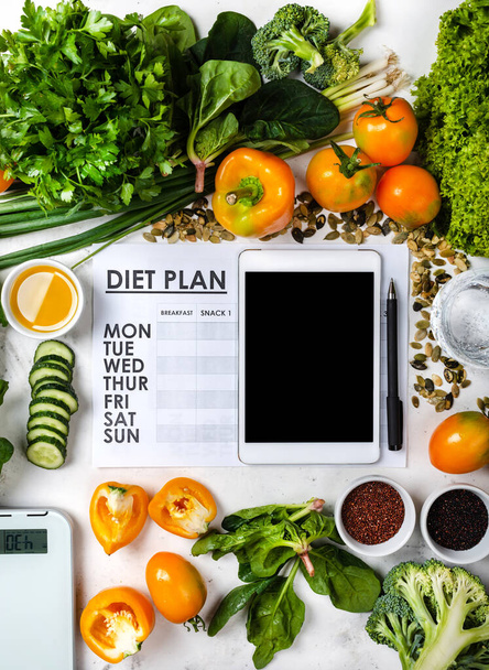 Να χάσω βάρος. Tablet υπολογιστή Διατροφή σχέδιο και σύνολο υγιεινών τροφίμων με κλίμακα κουζίνας - Φωτογραφία, εικόνα