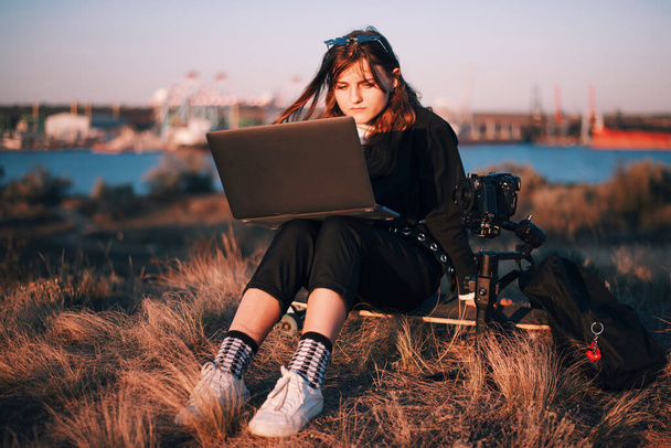 女の子は港のカメラの近くのノートパソコンで働いています - 写真・画像