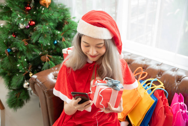 Frohe Weihnachten und ein gutes neues Jahr!. Junge Frau im roten Weihnachtsmann-Kleid mit Einkaufstaschen. - Foto, Bild