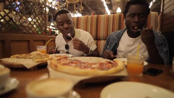 二人のアフリカ系アメリカ人の男はレストランで面白いピザを食べる - 映像、動画