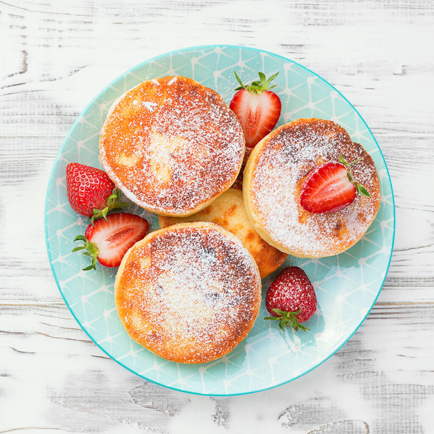 Cottage cheese pancakes with sliced strawberry on white background for breakfast. - Photo, Image