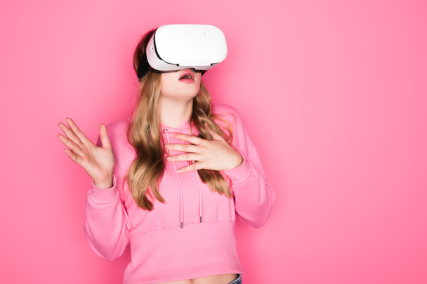 scared beautiful woman in vr headset on pink background - Foto, imagen