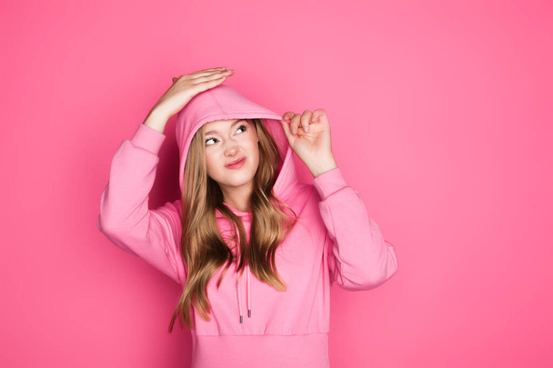beautiful young woman in hoodie on pink background - Фото, зображення