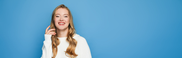 happy blonde beautiful woman in sweater isolated on blue background, banner - Foto, Bild