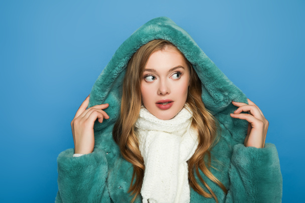 stylish woman in green faux fur coat looking away isolated on blue - Photo, Image