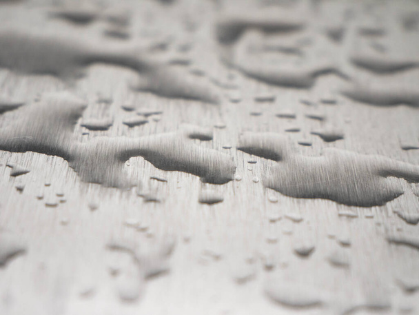 Gotas de agua goteando sobre una superficie metálica gris - Foto, imagen