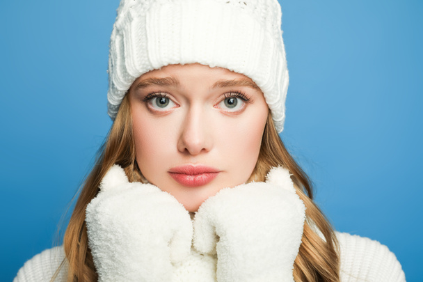 portrait of sad beautiful woman in winter white outfit isolated on blue - Photo, Image