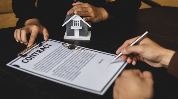 Agent nieruchomości lub kierownik sprzedaży zaproponował warunki do klientów, którzy podpisują umowy kupna domu z ubezpieczeniem, Umowa na podpisanie koncepcji umowy kupna. - Zdjęcie, obraz