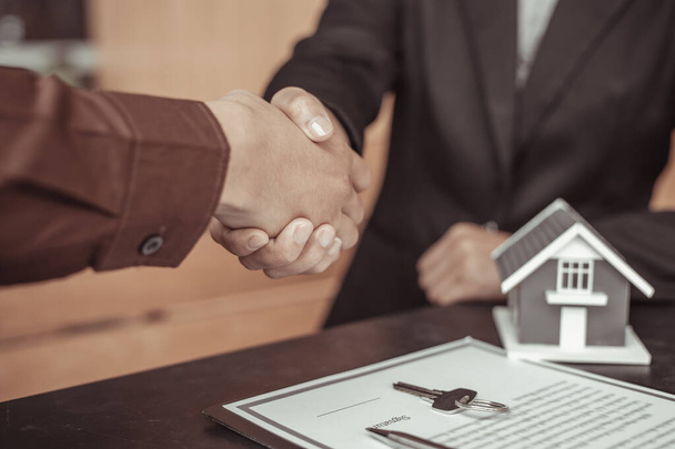 Agentes inmobiliarios y clientes se dan la mano para felicitar a la firma de un contrato para comprar una casa con tierra y seguros, apretón de manos y buen concepto de respuesta. - Foto, imagen