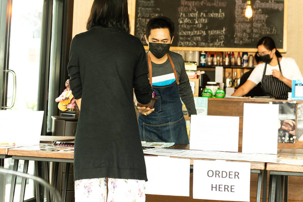 Social distance conceptual small business waiter serving customer in cafe - Photo, Image