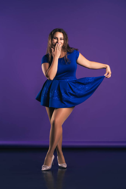 Happy plus size model in blue dress on purple background, body positive concept - Photo, image