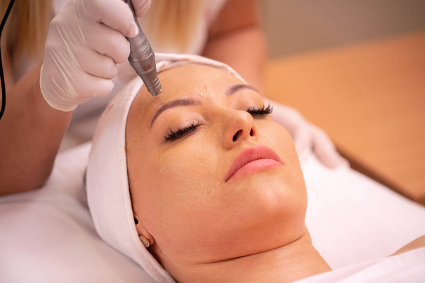 Middle aged woman having a electronic acupuncture pen treatment in cosmetics salon - Foto, Imagem