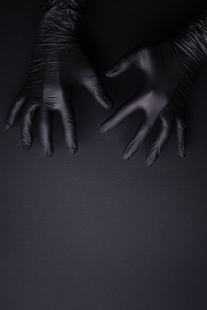 Hands in black gloves on black background. - Foto, Bild