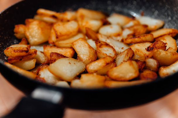 Pezzi di patata fritti nella padella. Cibo nocivo da vicino. - Foto, immagini