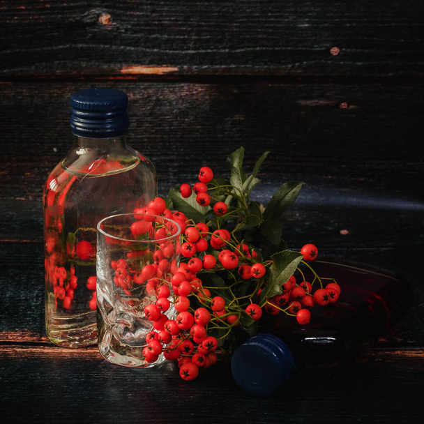 Γυάλινο μπουκάλι και rowanberry - Φωτογραφία, εικόνα