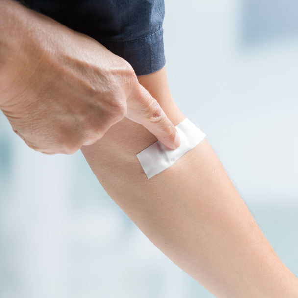 man's finger pressing on adhesive tape after taking of a blood sample - Fotó, kép