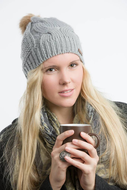 Mladý pěkný blondýnka žena v zimním oblečení s šálkem horkého nápoje  - Fotografie, Obrázek