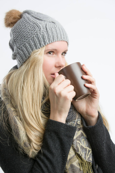 Joven mujer bonita en ropa de invierno disfrutando de una taza de bebida caliente  - Foto, Imagen