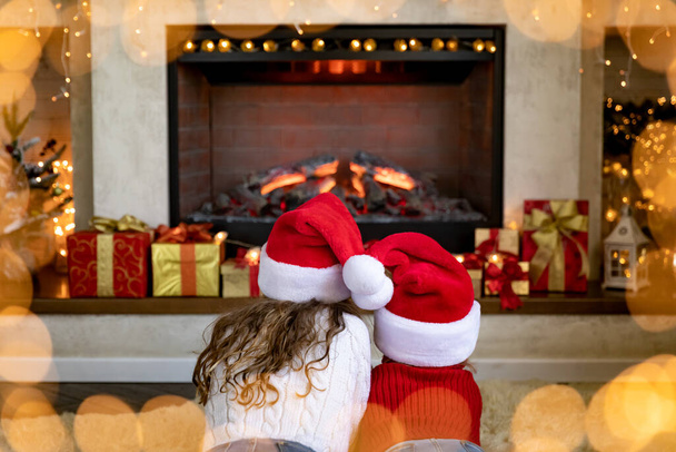 Happy children near fireplace at Christmas. Kids having fun at home. Xmas holiday concept - Foto, imagen
