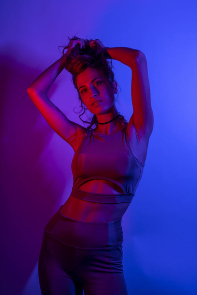 High Fashion model woman in colorful bright neon blue and purple lights posing in studio. Portrait of beautiful girl with trendy glowing make-up. Art design vivid style    - Photo, Image