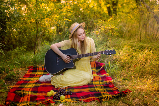 image of a girl in a straw hat playing the guitar in the park - Fotó, kép