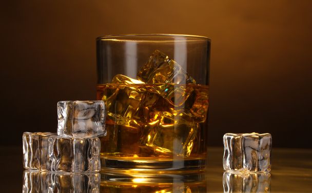 glass of whiskey and ice on brown background - Zdjęcie, obraz