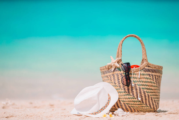 Strand kiegészítők - szalma táska, kalap és napszemüveg a strandon - Fotó, kép