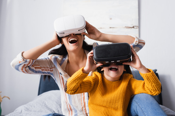 excited child with mother using vr headsets in bedroom - Photo, image