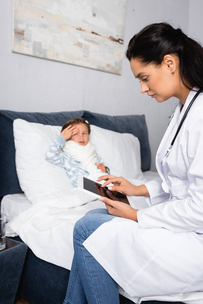 beteg lány megérinti homlok használata közben orvos digitális tabletta - Fotó, kép