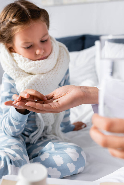 doctor giving pill and glass of water to sick girl on blurred foreground - Foto, Bild