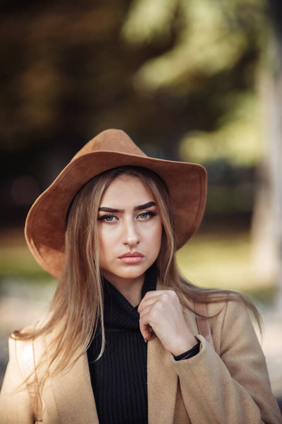 Retrato de uma mulher atraente com maquiagem vestida com um casaco e chapéu de feltro. Caminhe no parque da cidade de outono - Foto, Imagem