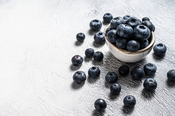 Blueberries in a white ceramic bowl. Gray background. Top view. Copy space - Foto, Imagen