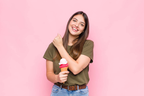 young pretty woman with an ice cream feeling happy, positive and successful, motivated when facing a challenge or celebrating good results - Foto, immagini