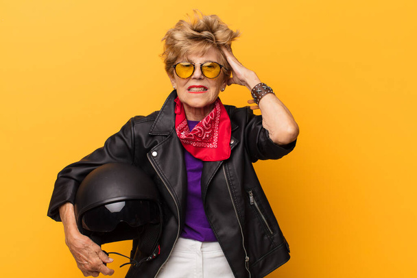 mature old beautiful woman feeling stressed, worried, anxious or scared, with hands on head, panicking at mistake. motorbike concept - Foto, immagini